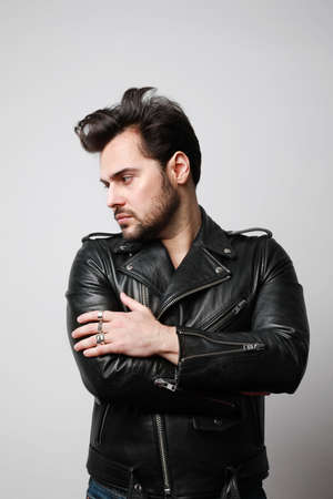 Vertical portrait of modern stylish young hipster man in a leather stylish jacket posing over a...