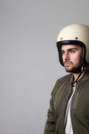 Shot brutal bearded biker man wears helmet and dressed in a green bomber jacket. Free space for text.の写真素材