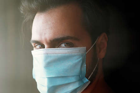 Man looking straight at the camera and wearing mask protection and recovery from the illness in...