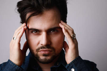 Close-up shot of bearded man in the denim outfit which mixed with bright white t-shirt posing over...