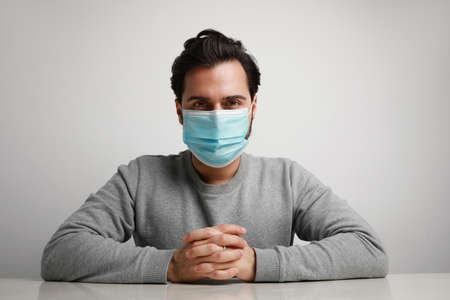 Young caucasian man in a blue medical mask on his face. Pandemia and quarantine. Stay at home.