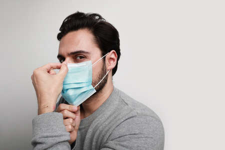 Side portrait of young man using medical mask protection of coronavirus. Worldwide pandemic situation. Space for text.の写真素材