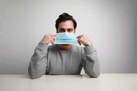 Headshot of young man using medical virus mask protection of coronavirus. Worldwide pandemic situation. Space for text.の写真素材