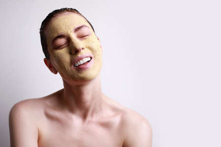Portrait of young caucasian woman applied facial mask with closed eyes isolated on grey background....