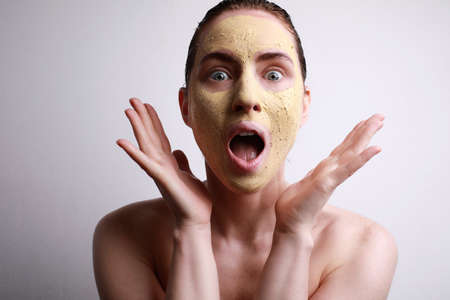 Surprising woman with moisturising facial mask with cute smile isolated on grey background. Beauty and skin care.の写真素材