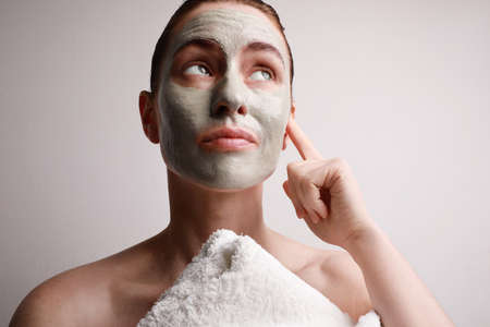 Beautiful woman with grimas face having clay facial mask applied.Looking aside.の写真素材