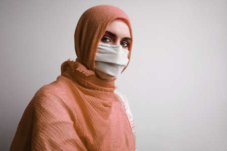 Young muslim woman in hijab wearing medical mask to prevent coronavirus Covid-19 worldwide pandemia.の写真素材