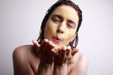 Close-up portrait of young caucasian woman with facial clay mask doing air kiss gesture. Space for...