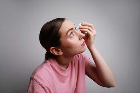 Woman has eye allergy and inserting eye-drop. Health care and eyesight concept. Conjuctivitis. Woman with injured eyeの写真素材
