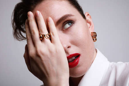 Close-up portrait of young confident woman with red lips, touching her face. Isolated over white...