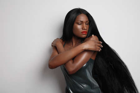 Beautiful black young woman with long hair posing over white background. Self confidence.の写真素材