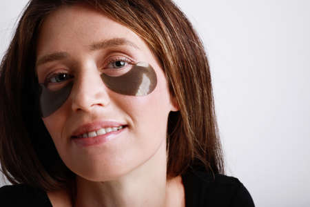 Attractive caucasian young woman with collagen eye pads isolated on white.の写真素材