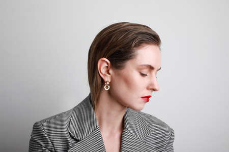 Attractive young woman in blazer and red lips, looking aside and smiling with friendly face. Copy space.の写真素材