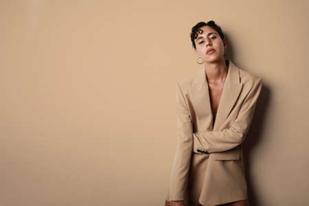 Sexy and beautiful woman fashion glamour model brunette hair, wear suit jacket clothes party style. Isolated beige wall.の写真素材