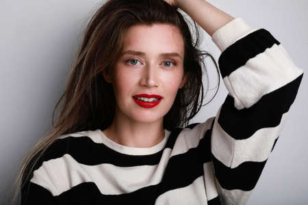 Young and attractive caucasian woman with red lips looking at the camera and smiling. Positive...