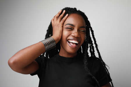 Close-up of young Black woman, smiling, having fun and posing over white background.