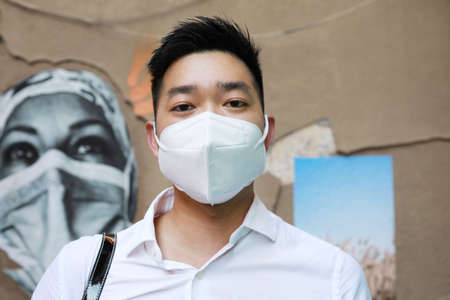 Covid-19, pandemic. Young Asian man with face mask to protect and prevent from the spread of viruses in the city.の写真素材