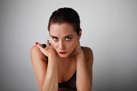 Beauty fashion portrait. Attractive young woman with evening make-up posing over grey wall...