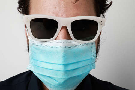 Portrait of 30-39 years old man wearing surgical mask and sunglasses. Pandemic situation. Covid-19.の写真素材