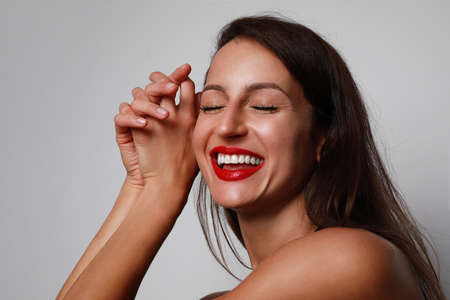 Beautiful young woman with a clean fresh face close-up with perfect smile. Posing over beige background.の写真素材