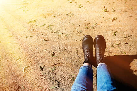 Autumn concept, close-up of black shoes with yellow leafs around.