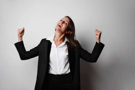Young dark-haired woman wearing white blouse posing against white background with hands up. Space for text.の写真素材