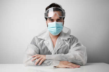 Headshot of young doctor in special suite wears a face mask as preventive measure of coronavirus COVID-19.の写真素材