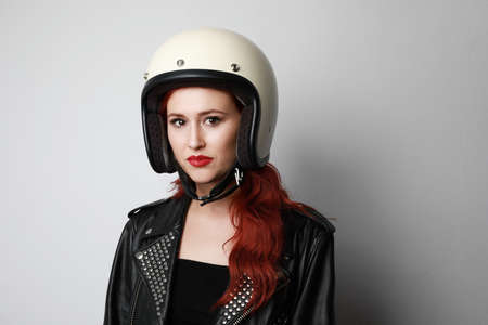 Attractive young biker woman, wearing white helmet and leather jacket, looking at the camera. Space for text.の写真素材