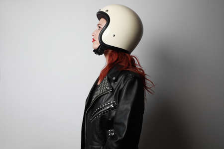 Side view portrait of young woman with a motorcycle helmet posing over isolated white background celebrating a victory.の写真素材