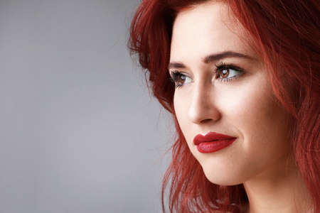 Close-up portrait of sensual woman with beautiful long red hair posing over white background. Space for text.の写真素材