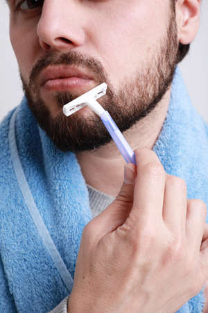 Vertical close-up of bearded man shaving in the morning. Isolated over white background.