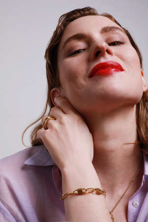 Close-up of caucasian woman with golden jewellery isolated on grey wall.の写真素材