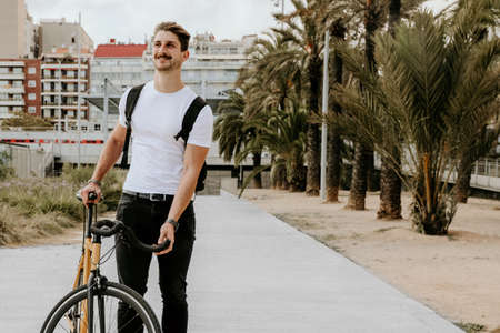 Outdoor shot of hipster wearing white t-shirt on bike in the city. Lifestyle.