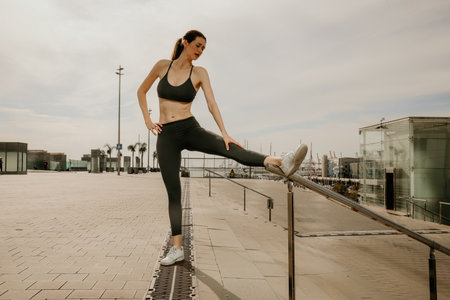 Caucasian sporty and young woman stretching body after jogging, posing outdoor.の写真素材