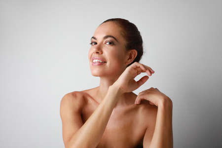 Portrait of cheerful happy mature woman with shoulder off posing over white wallの写真素材