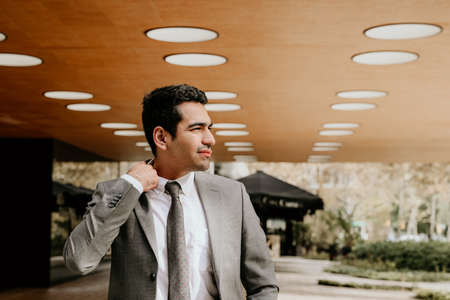 Handsome businessman walking outdoors with office building in the background.の写真素材