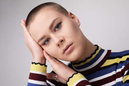 Portrait of young bald woman with non-perfect skin, posing on white background.