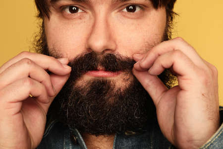 Portrait of confident joyful plump men with moustache standing over yellow wall.の写真素材