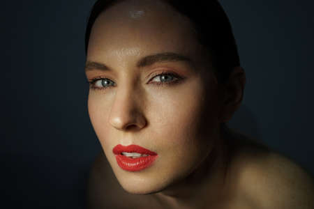 Beauty close-up portrait of young woman, posing over black background.