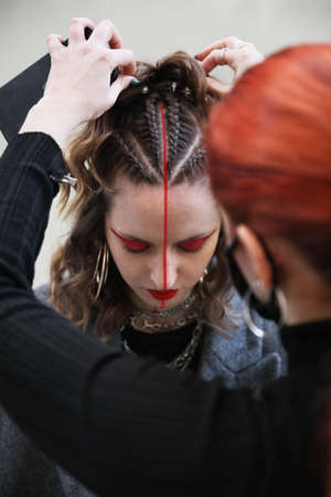 Young women making braids hair style. Vertical.