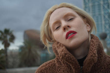 Outdoor headshot portrait of young woman with blonde hair.