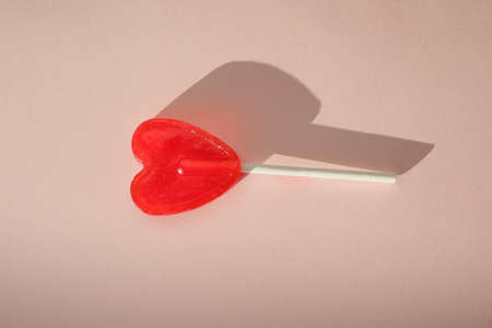 Red candy in the form of a heart on a stick. Mock-up San Valentine day.