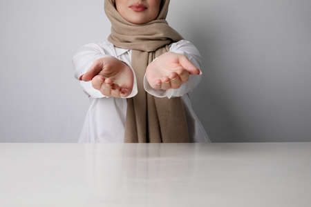 Portrait of young happy muslim woman giving hands of help. Isolated.の写真素材