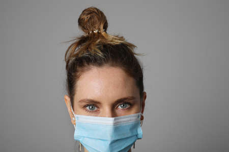 Close-up of young woman wearing surgical blue mask for corona virus. Pandemic.の写真素材
