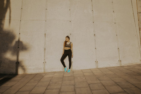 Female runner standing outdoors, taking a break after running workout.の写真素材