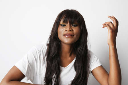 A black African woman with surprising face expression, posing over white wall.