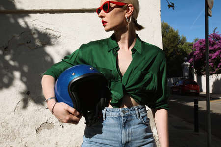 Young woman outdoor holding motorcycle helmet on street and looking awayの写真素材