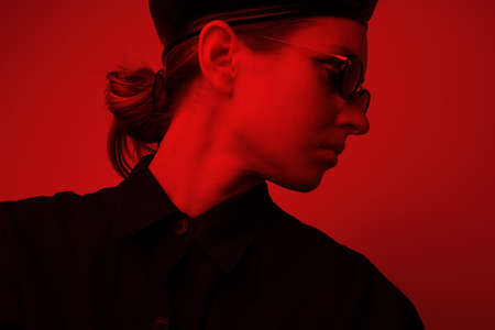 Portrait of young woman with red lightening, looking aside wearing sunglasses.の写真素材