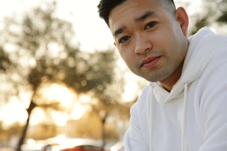 Headshot of handsome smiling young Asian man, posing outdoor.の写真素材