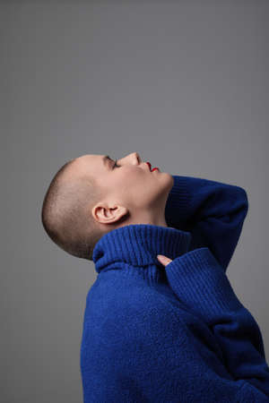 Close-up portrait of beautiful bald young woman, wearing blue sweater. Vertical.の写真素材